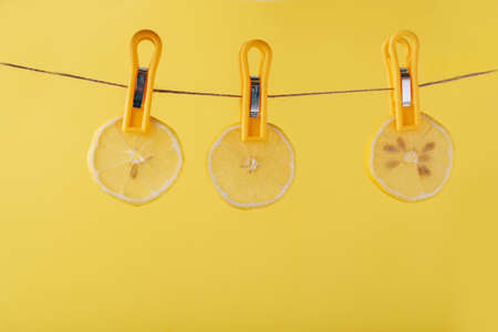 Lemon slices on a clothespin on a rope on a yellow backgroundの写真素材
