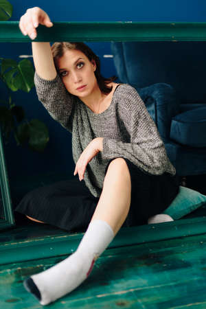 Beautiful young woman in gray sweater and disco ball at home