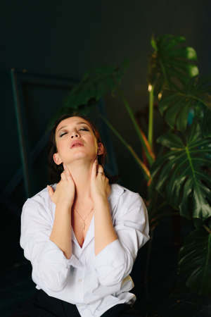 Portrait of a beautiful young woman in a white shirt and black trousers at homeの写真素材