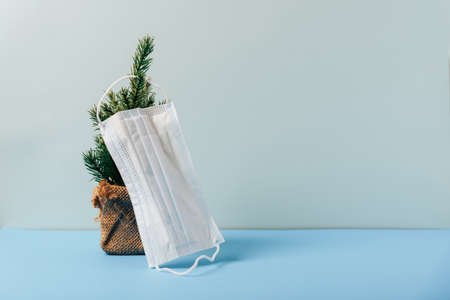 Christmas layout with a Christmas tree and a medical mask on a blue background