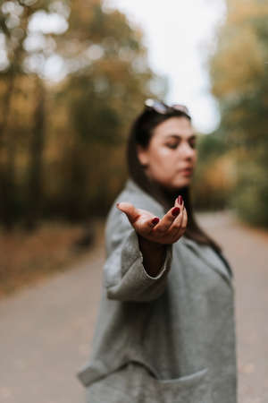 Beautiful woman in a gray coat on an autumn alley. Blurry portrait of a womanの写真素材