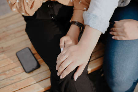 Two young adult lesbian women holding hands. Women's hands close upの写真素材