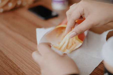 Close-up of a woman's hands with French fries in a street cafeの写真素材