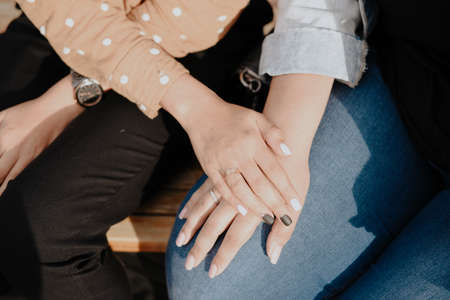 Two young adult lesbian women holding hands. Women's hands close upの写真素材
