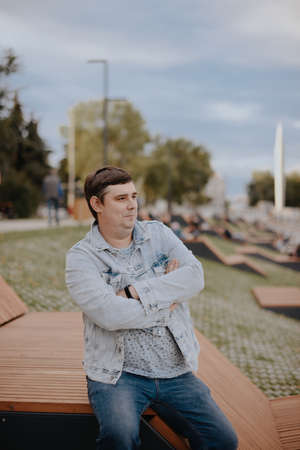 Adult young man in a city Park in a denim jacketの写真素材