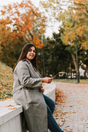 Portrait of a beautiful adult young woman on the background of autumn in the Parkの写真素材
