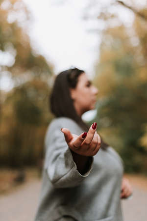 Beautiful woman in a gray coat on an autumn alley. Blurry portrait of a woman
