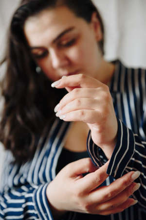 Hands of a girl close up on the background of a girl's faceの写真素材
