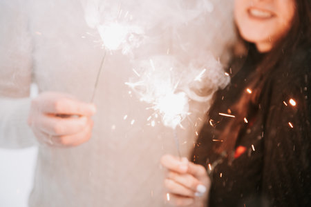 A man and a woman with sparklers on the background of a snow-covered forest in a snowfallの写真素材