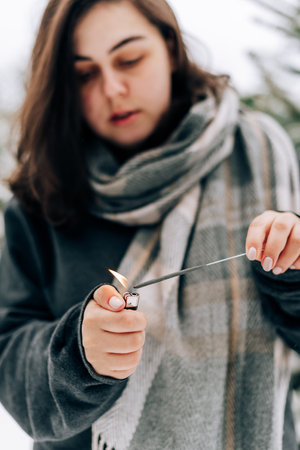 Adult young woman with sparklers on the background of winter pine forest