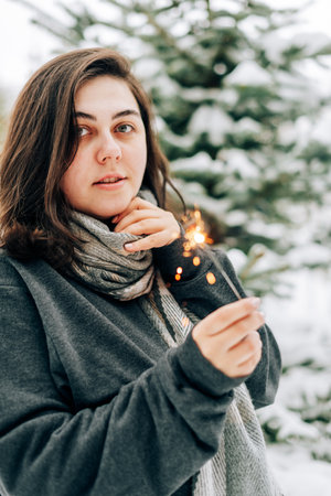 Adult young woman with sparklers on the background of winter pine forest