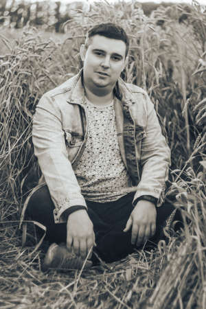 A young man in a field with green wheatの写真素材