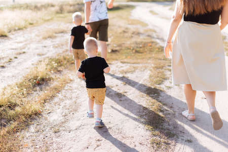 A young family with two children walks in nature outside the city in the summerの写真素材