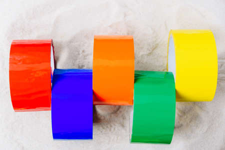 Colored scotch tape on white sandの写真素材