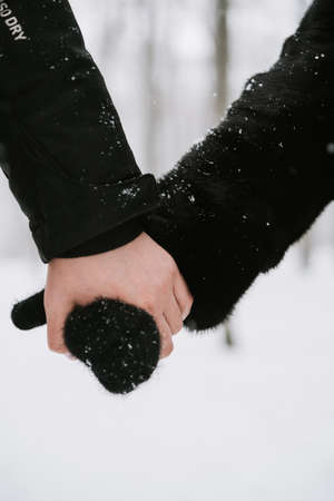 A man holds a womans hand in a mitten close-up