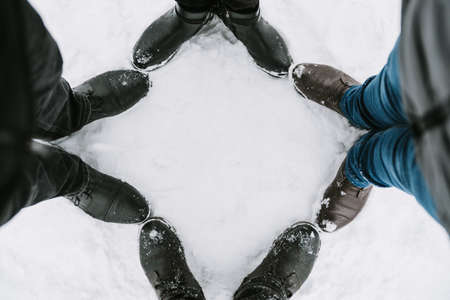 Feet of four people in the snow close-upの写真素材