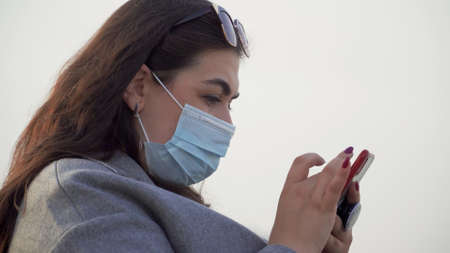 A young woman with a phone in her hands wearing a maskの写真素材