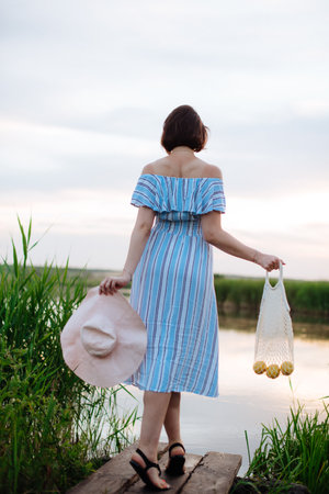Beautiful young woman on the lake at sunsetの写真素材