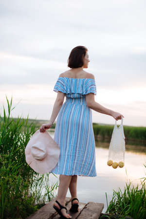 Beautiful young woman on the lake at sunsetの写真素材