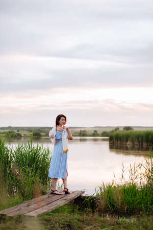 Beautiful young woman on the lake at sunsetの写真素材