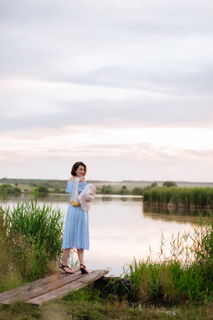Beautiful young woman on the lake at sunsetの写真素材