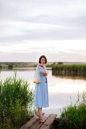 Beautiful young woman on the lake at sunsetの写真素材