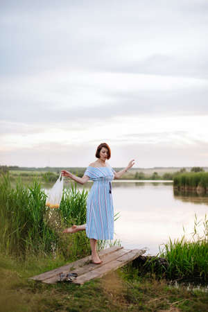 Beautiful young woman on the lake at sunsetの写真素材