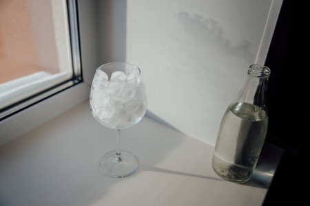 A glass with ice and a bottle of water