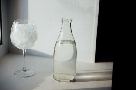 A glass with ice and a bottle of waterの写真素材