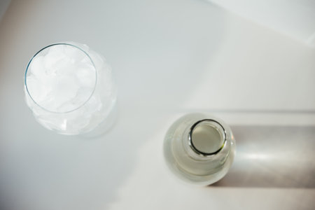A glass with ice and a bottle of waterの写真素材