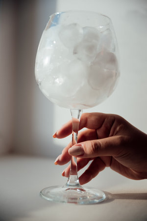 A woman's hand holds a glass with iceの写真素材