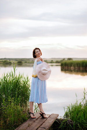 Beautiful young woman on the lake at sunsetの写真素材