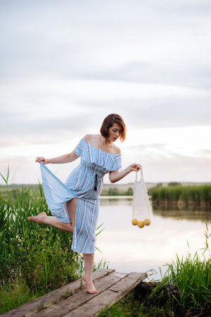 Beautiful young woman on the lake at sunsetの写真素材