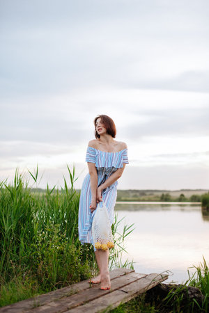Beautiful young woman on the lake at sunsetの写真素材