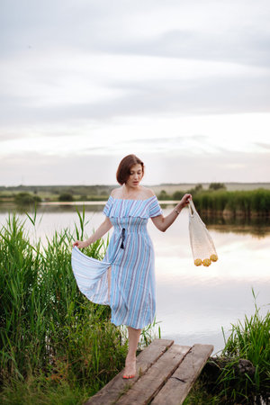 Beautiful young woman on the lake at sunsetの写真素材