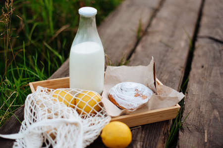 A bottle of milk and a string bag with fruit on wooden boards on the lake 1の写真素材