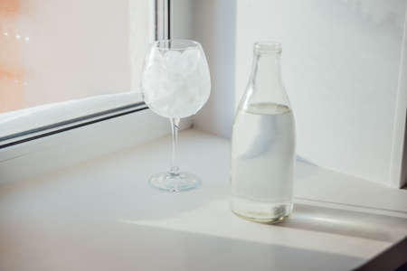 A glass with ice and a bottle of waterの写真素材