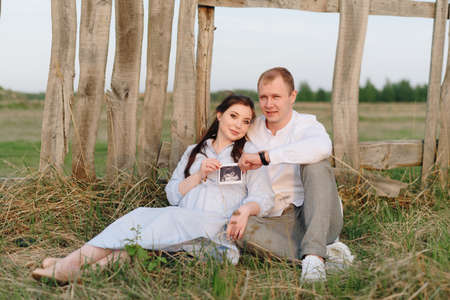 Young heterosexual pregnant couple in an outdoor parkの写真素材