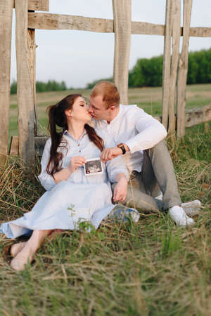Young heterosexual pregnant couple in an outdoor parkの写真素材