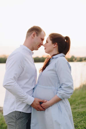 Young heterosexual pregnant couple in an outdoor parkの写真素材