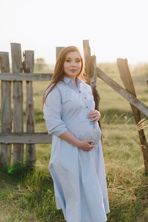 Pregnant girl in summer outdoors in the setting sunの写真素材