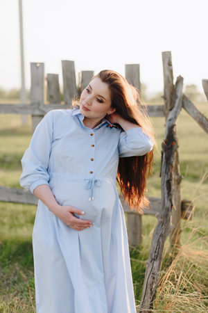 Pregnant girl in summer outdoors in the setting sunの写真素材