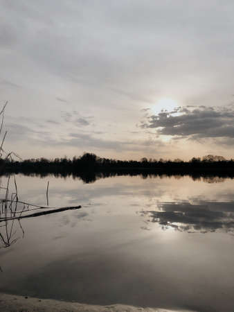 Beautiful sunset over an autumn lake and dry plantsの写真素材