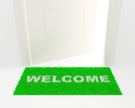 The slightly opened white door and green rug with an inscription: Welcome.の写真素材