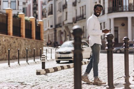 Man with smartphone walking and smiling stock photoの写真素材