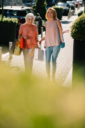 Positive ladies strolling with shopping bags in handsの写真素材
