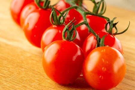 Beautifully shaped cherry tomatoes lying on wooden surfaceの写真素材