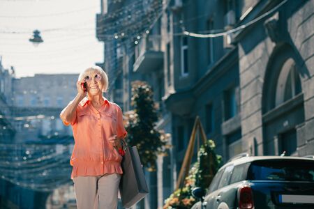Happy pensioner walking alone and having phone talkの写真素材