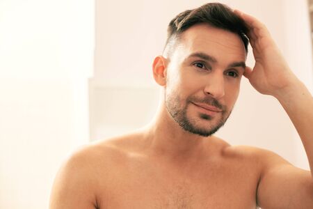 Smiling man touching his hair and looking awayの写真素材