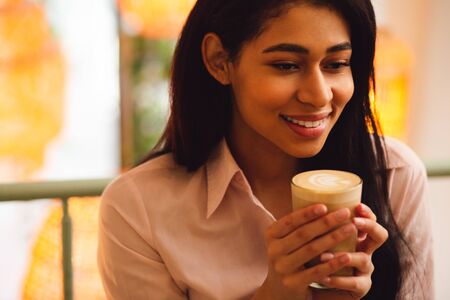 Calm lady enjoying tasty latte and smiling